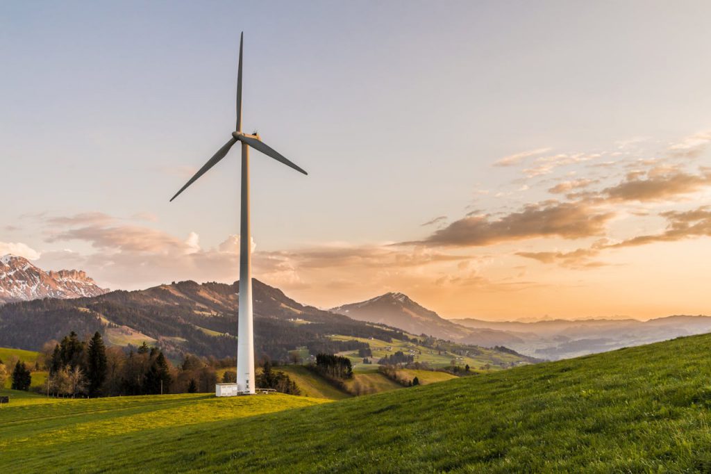 pexels-photo-414837 Wind turbine amid rolling hills and mountains at sunset, symbolizing renewable energy and sustainability.