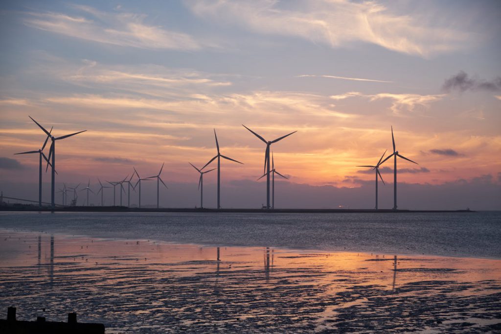 pexels-photo-532192 Wind turbines on the shoreline silhouette against a vibrant sunset, promoting renewable energy.